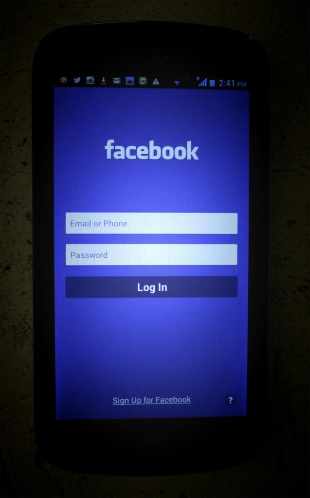Dark smartphone screen showing Facebook login page with input fields.